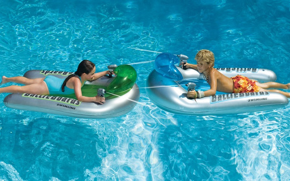children floating and squirting each other on inflatable battle boards