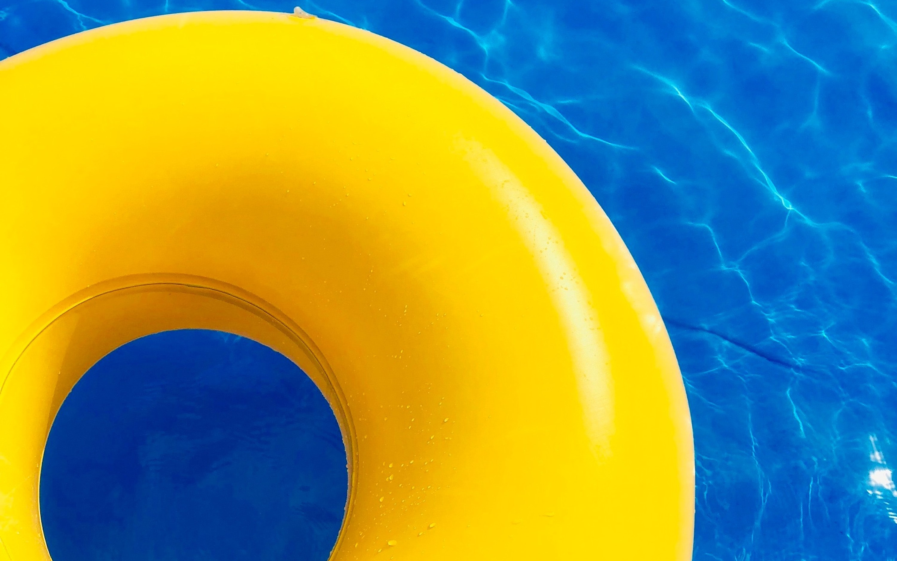 bright yellow pool ring floating in blue pool water