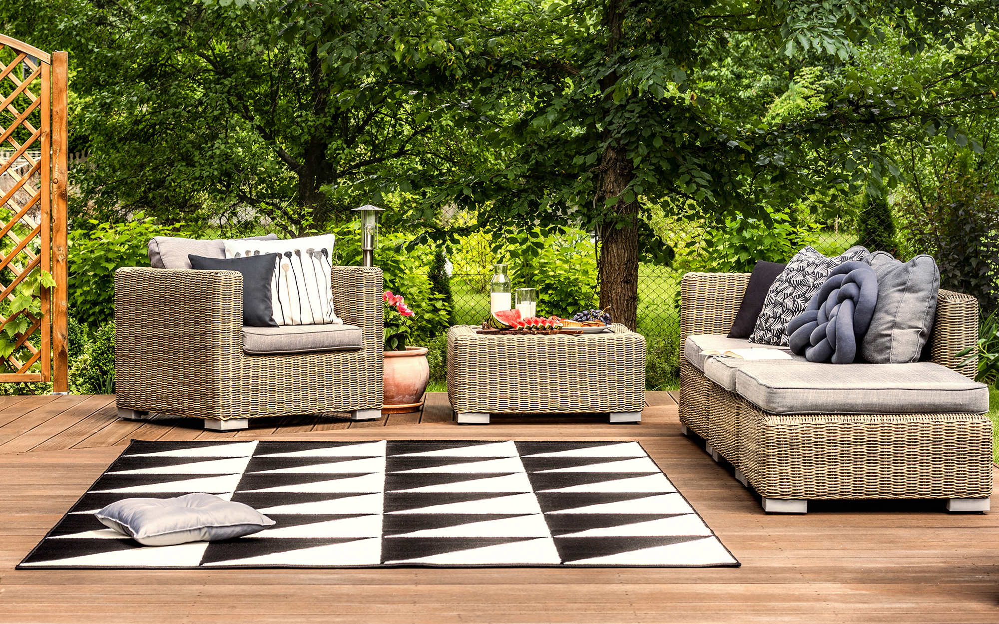 wicker patio on outdoor deck with black and white geometric outdoor rug