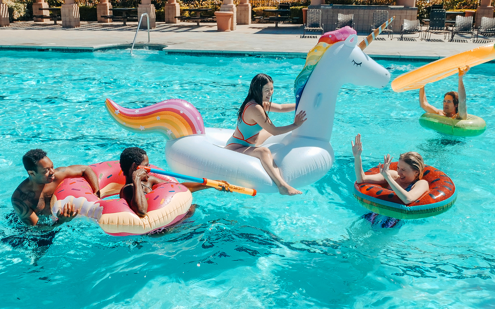 group of young adults on pool floats in swimming pool
