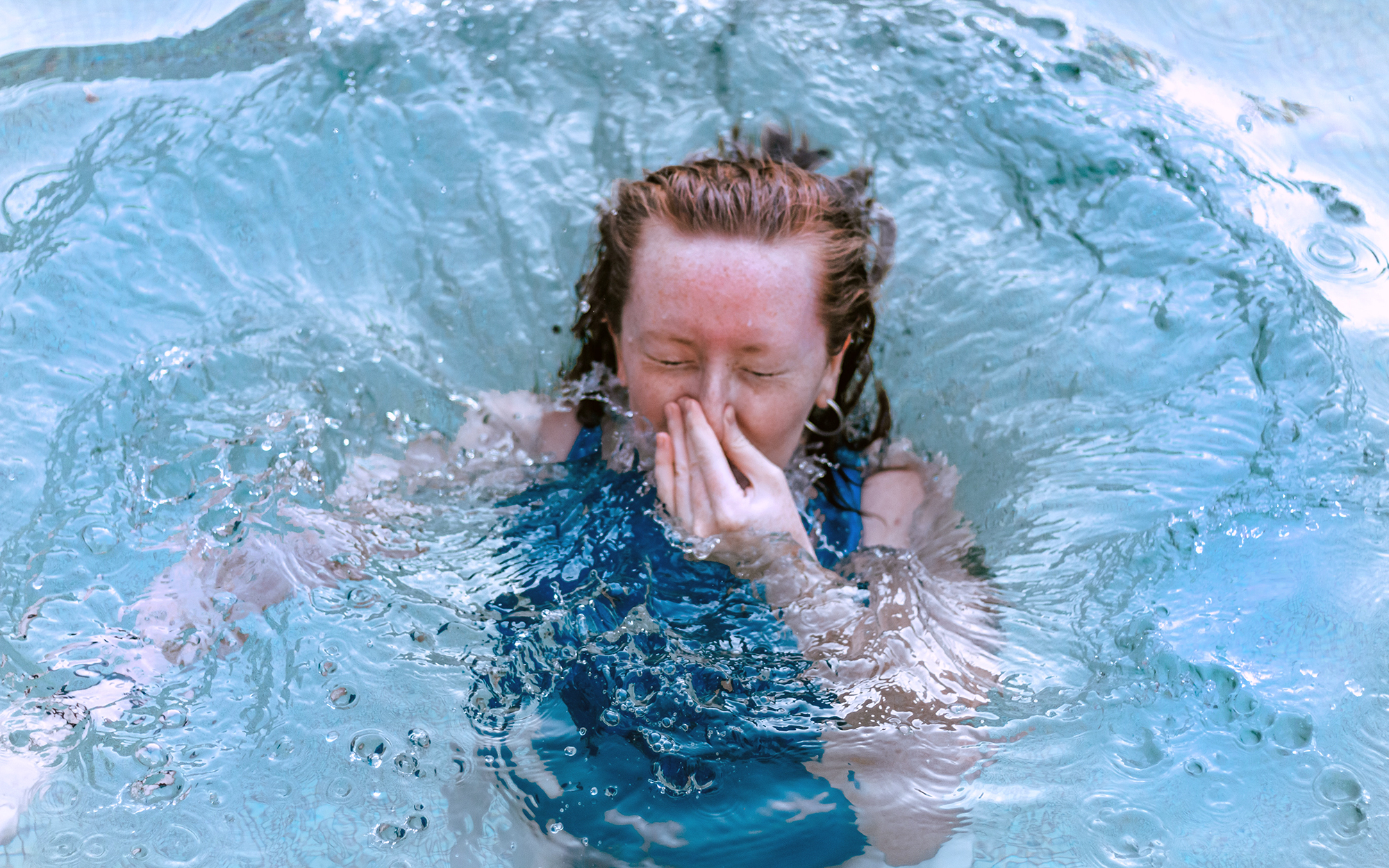 teen girl holding breath in water. Breath-holding games should b discouraged as they can lead to passing out in the water.