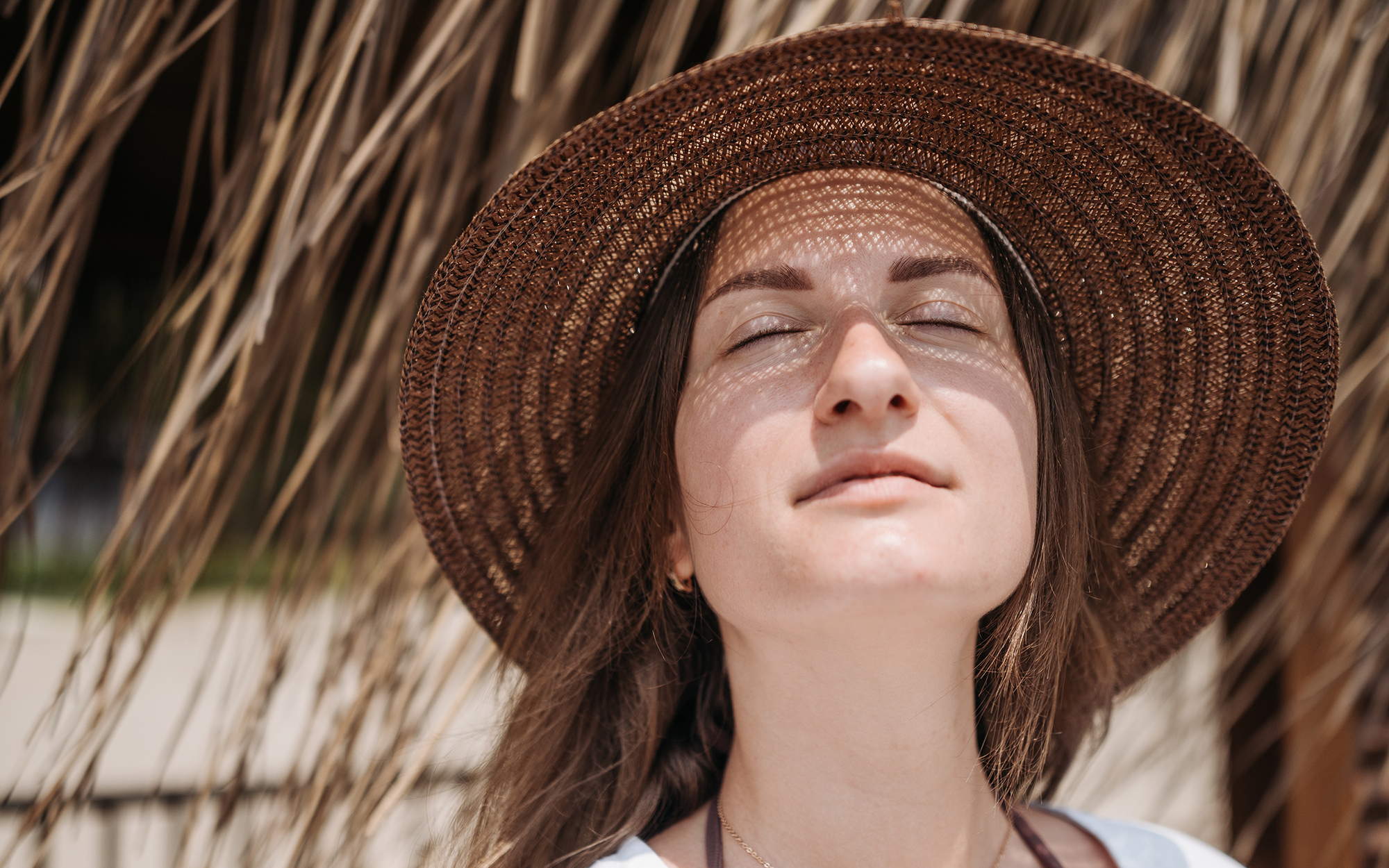 woman wearing straw hat with face raised toward sun woman wearing straw hat with face raised toward sun